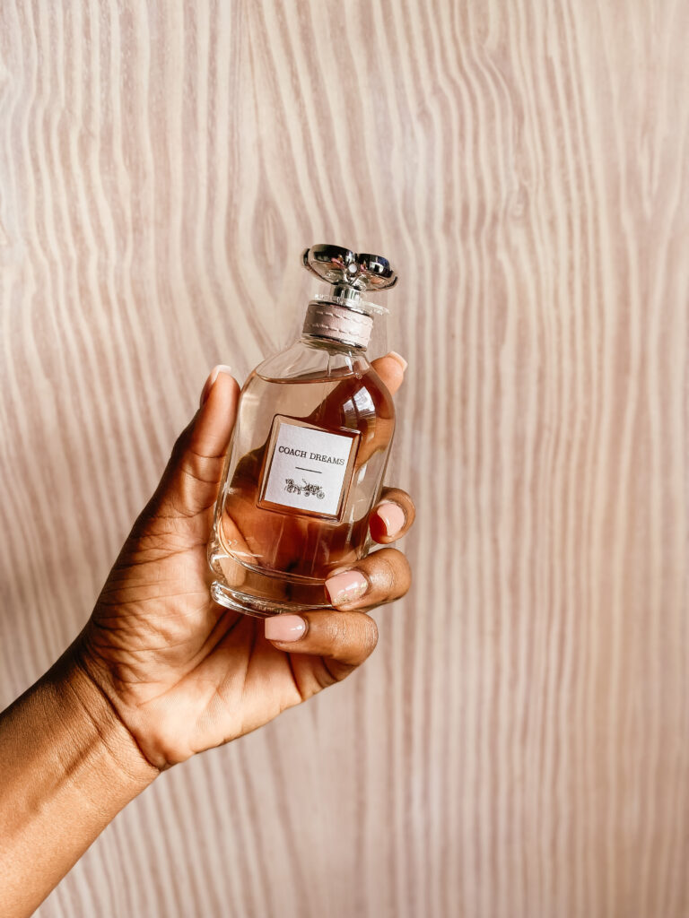 coach perfume in hand wooden background